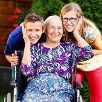 Lady in wheelchair with her carers smiling