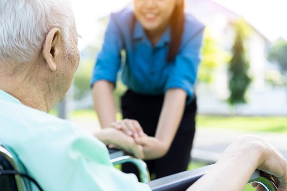 Elderly man in wheelchair with young carer