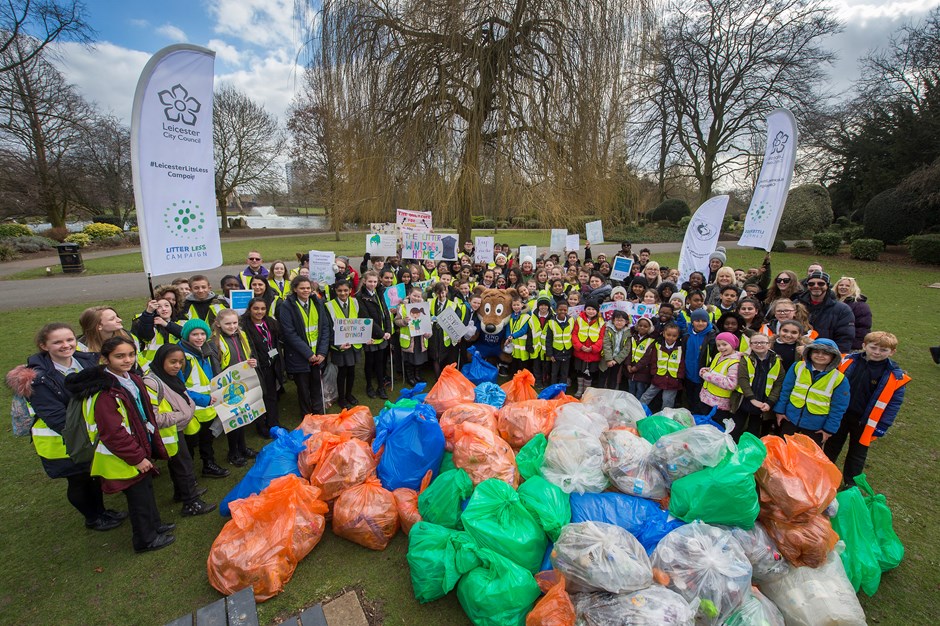 Children and adults posing with collected rubbish after a clean up campaign