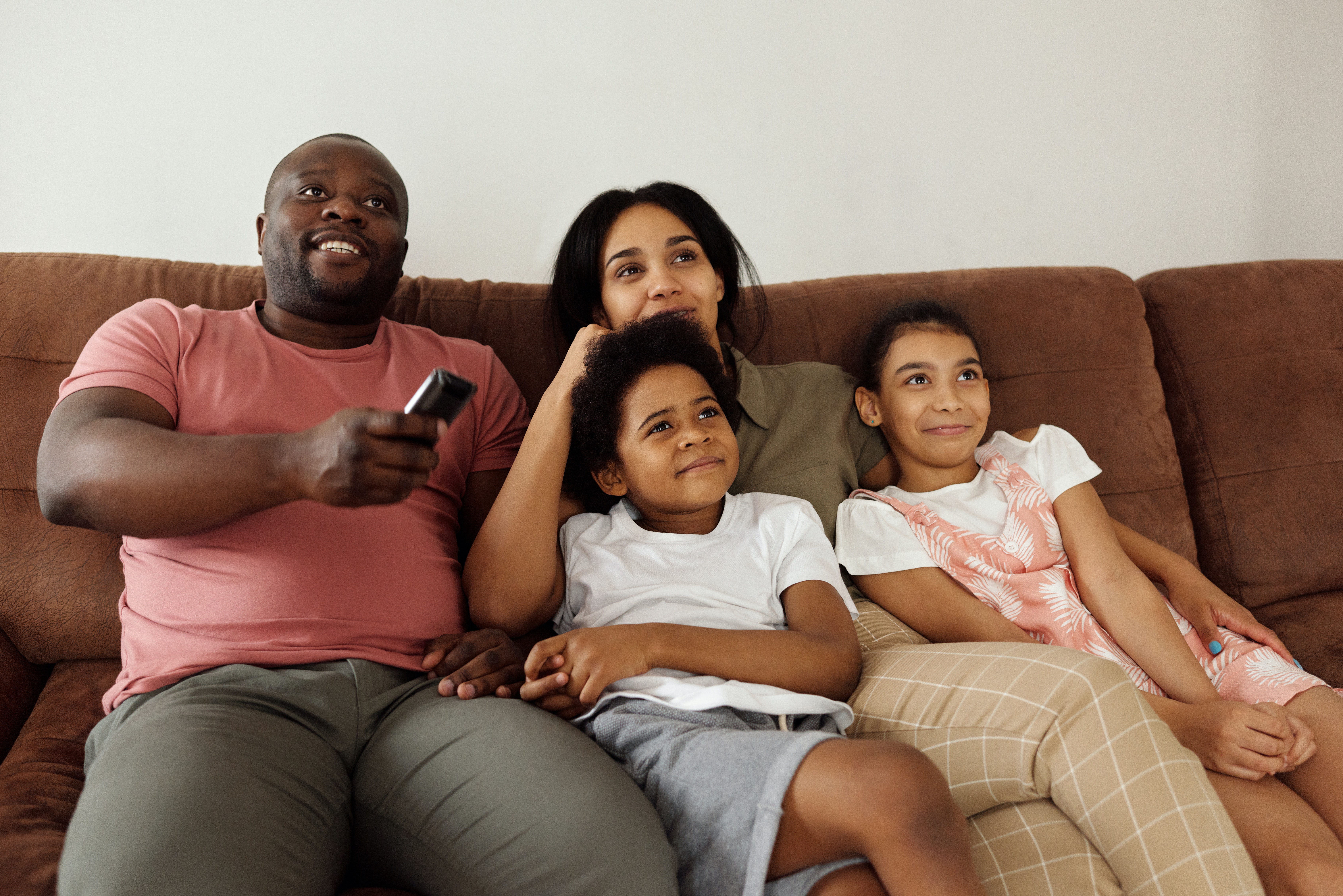 Family sat on sofa with TV remote in hand